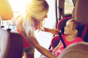 Mother securing baby in car seat.