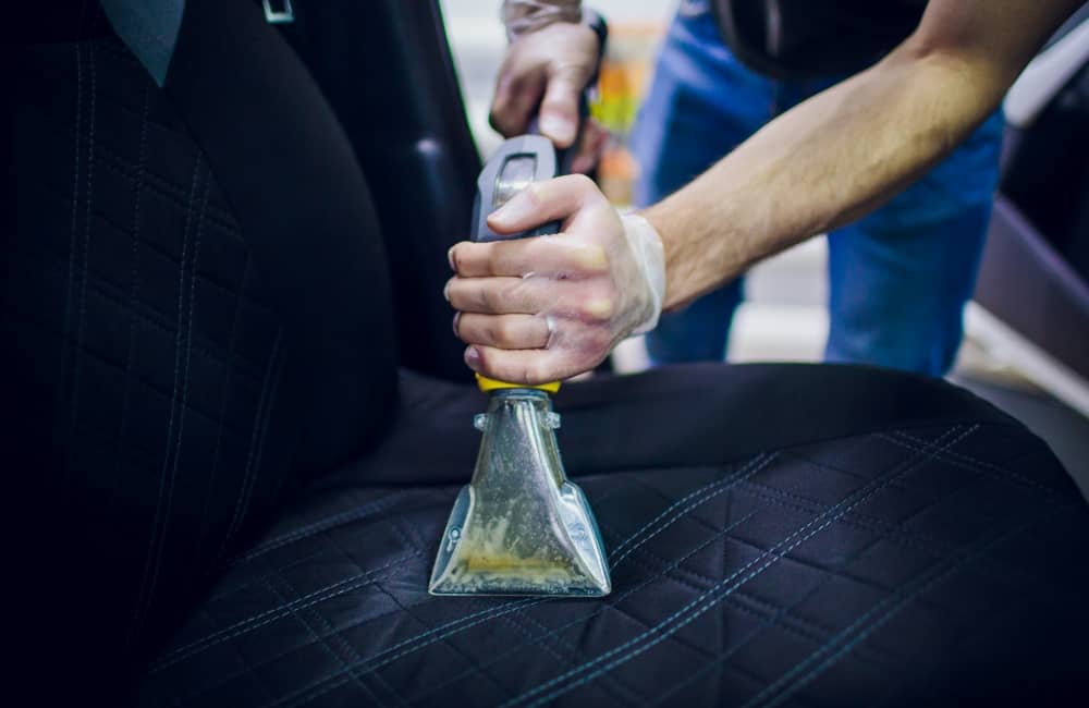 Cleaning car seat cover with vacuum.