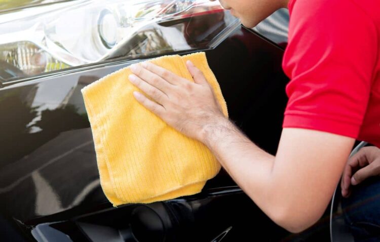 Man wiping car using microfibre cloth.